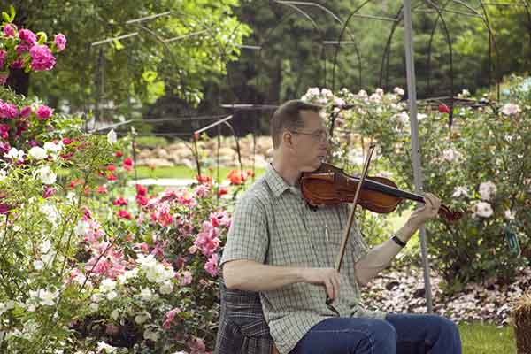 Jim McKinney fiddling in the flowers